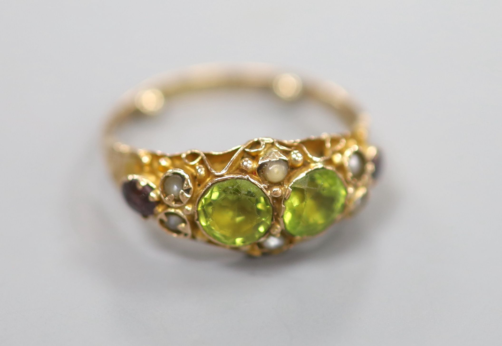 A George V 9ct gold, peridot, seed pearl and garnet set dress ring, in the Suffragette colours, size K, gross 2 grams.